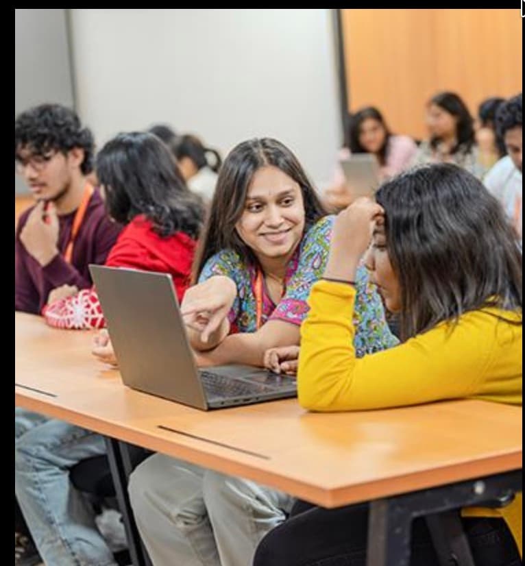 BBA students collaborating on a laptop in class